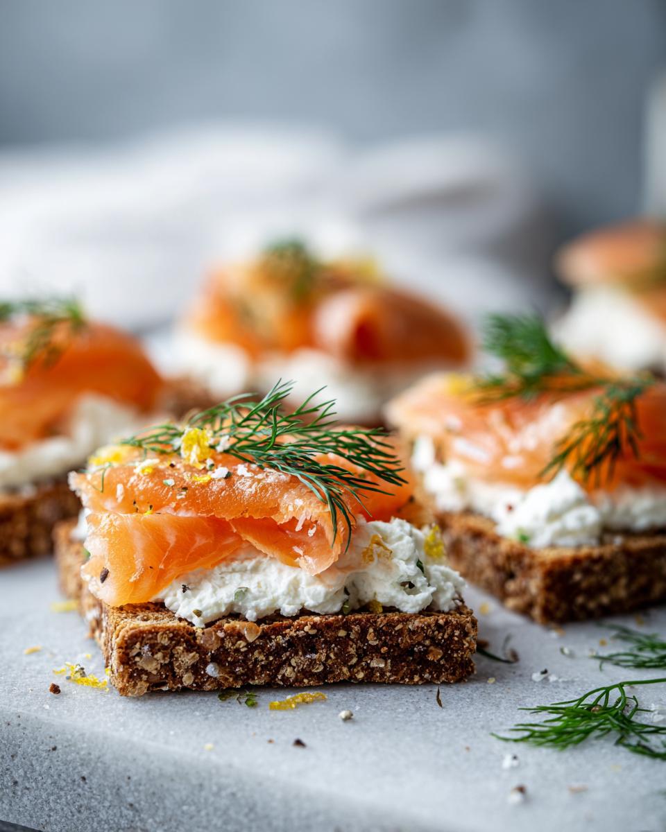 Primer plano de aperitivos de año nuevo con salmón ahumado, queso crema y eneldo sobre pan integral.