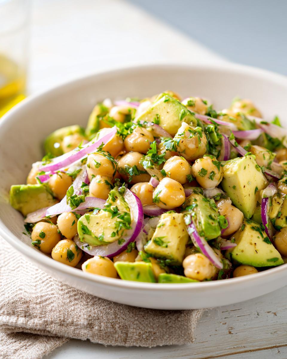 Ensalada de garbanzos y aguacate con cebolla morada y perejil, ideal para cenas rápidas y baratas.