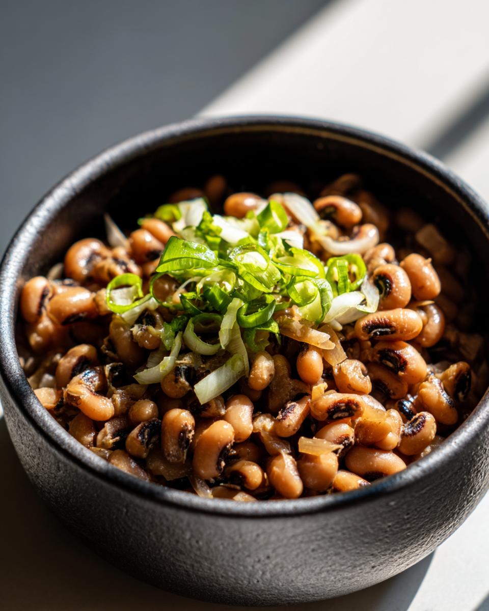 Primer plano de un tazón de frijoles caritas cocidos, adornados con cebolla verde picada.