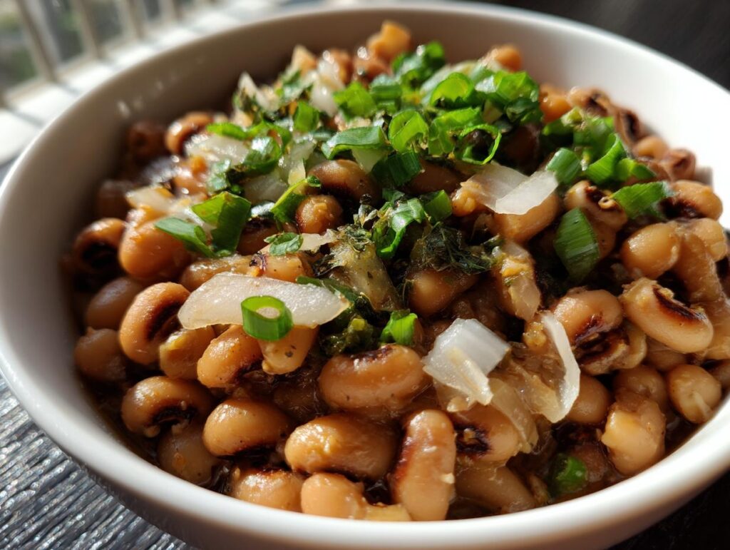 Primer plano de un tazón de frijoles caritas cocidos, adornados con cebolla picada y cebollín.