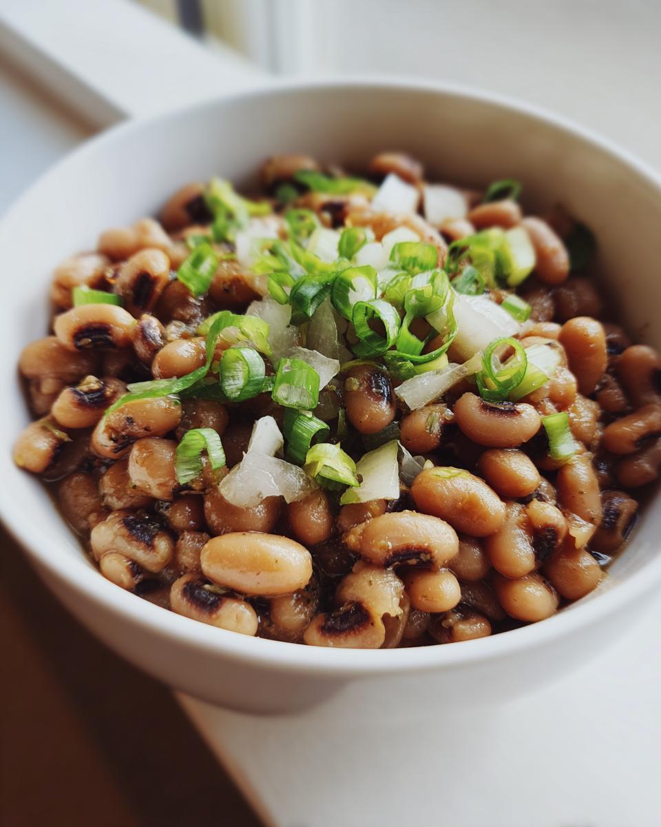 Primer plano de un tazón de frijoles caritas cocidos, adornados con cebolla picada y cebolleta.
