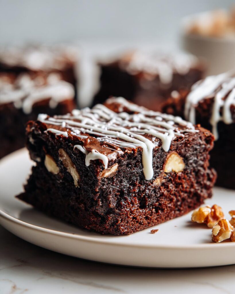 Brownies navideños con nueces y glaseado blanco sobre un plato blanco.