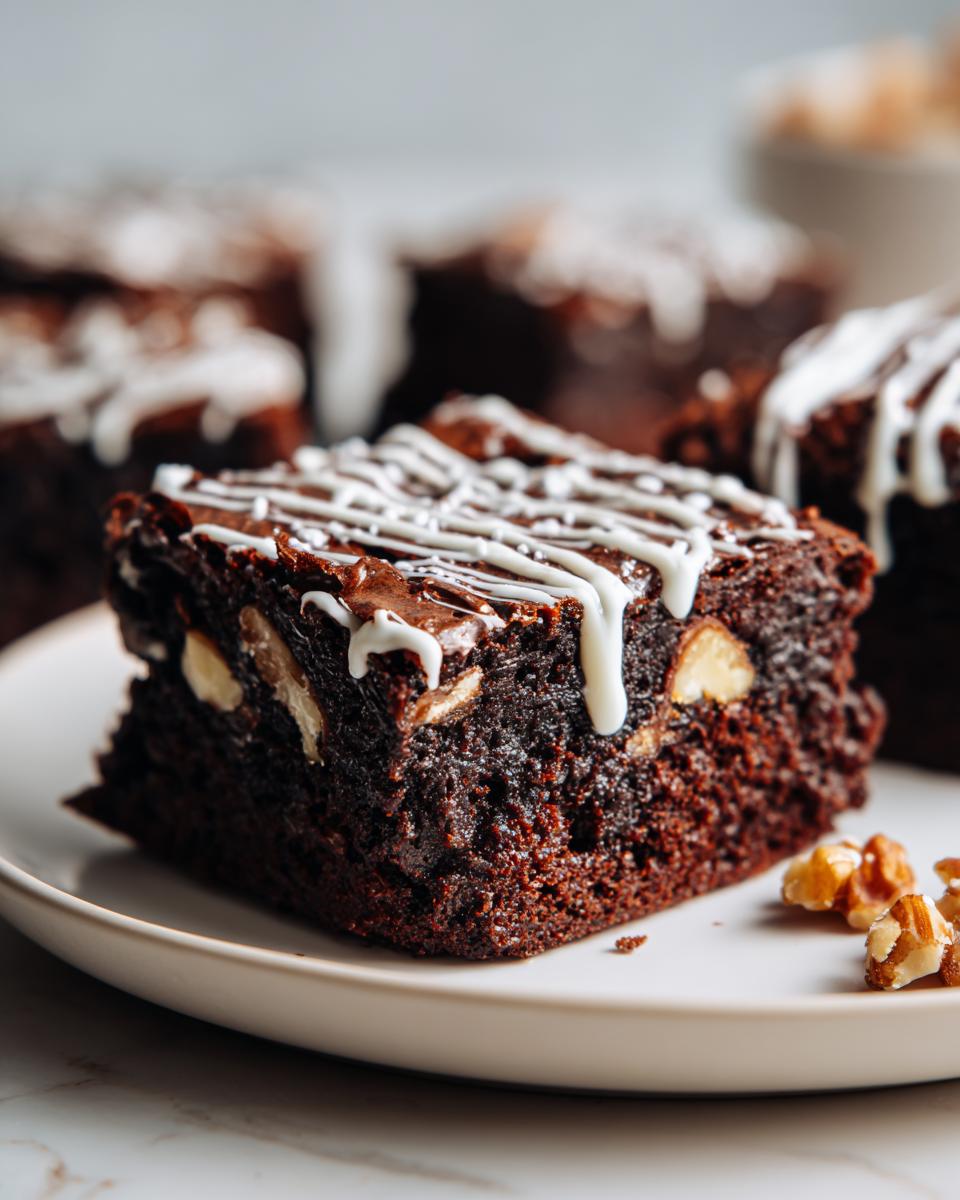 Brownies navideños con nueces y glaseado blanco sobre un plato blanco.