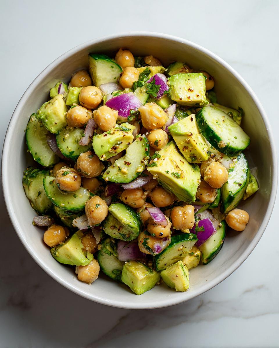 Ensalada con garbanzos, aguacate, pepino y cebolla morada en un bowl blanco para cenas sin carne rápidas