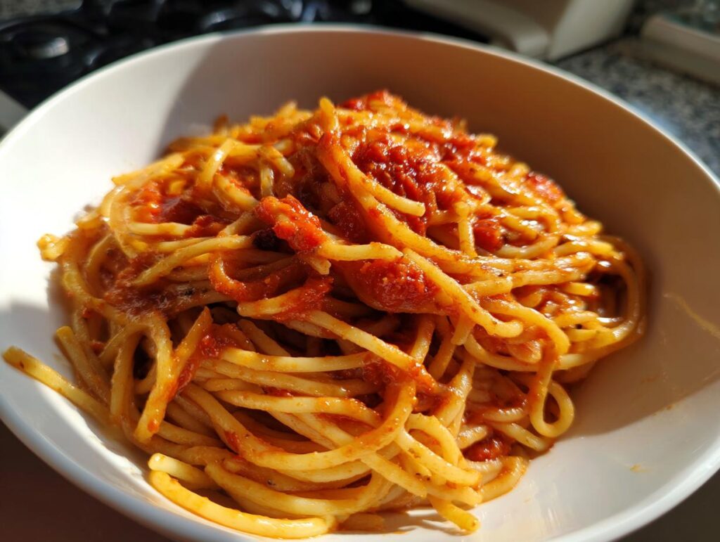 Plato blanco con espaguetis cubiertos de salsa de tomate, ideal para recetas económicas San Valentín.