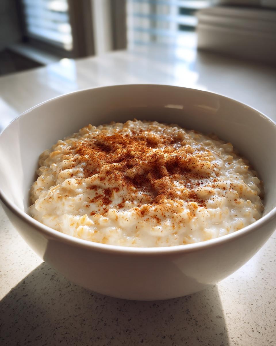 Tazón blanco con gachas de avena cremosas espolvoreadas con canela en polvo