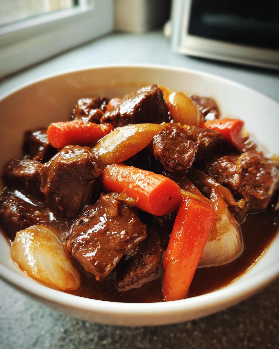 Plato de guisos a fuego lento caseros con carne, zanahorias y cebollas en salsa.