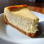 Porción de tarta de queso San Valentín con base de galleta en plato blanco bajo luz natural