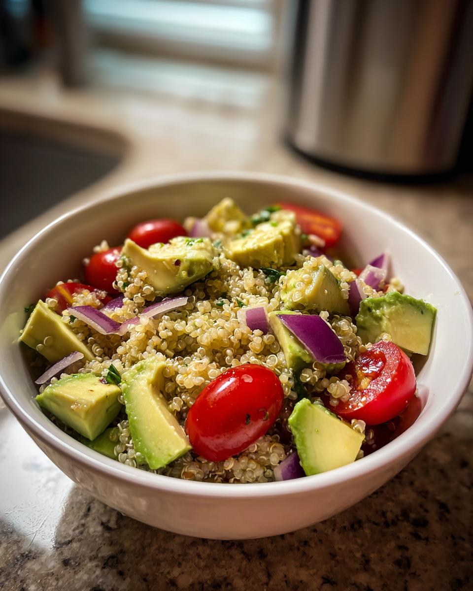 Ensalada con quinoa, aguacate, tomate cherry y cebolla morada en un bol blanco