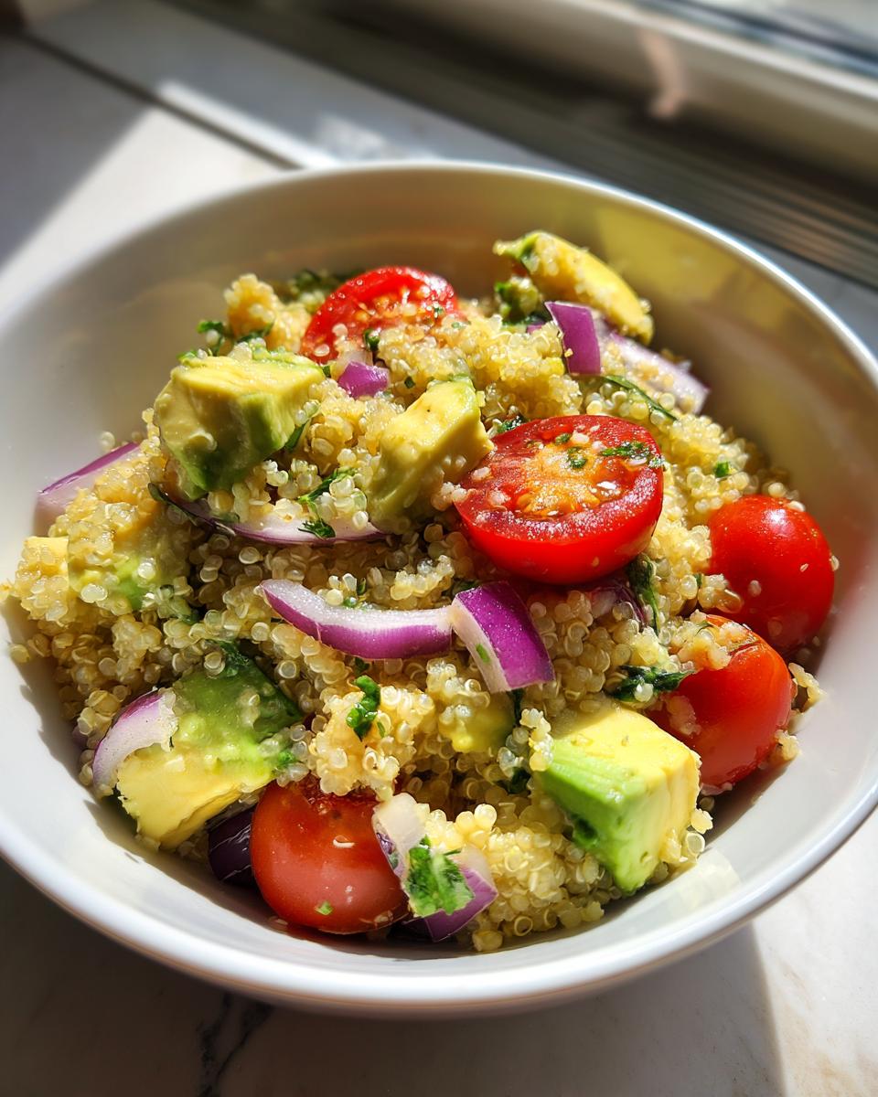 Ensalada con quinoa, aguacate, tomates cherry y cebolla morada en un bol blanco