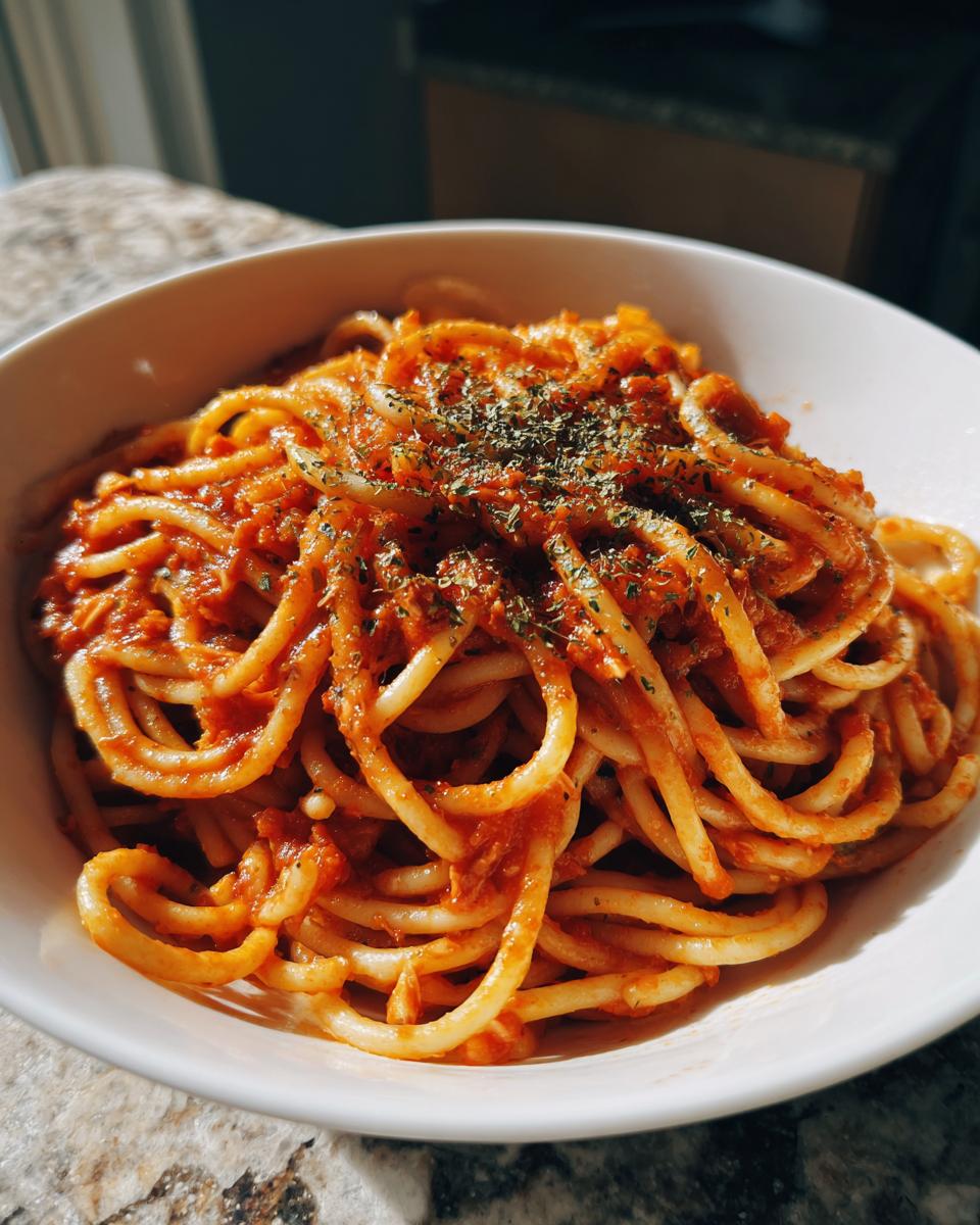 Espaguetis con salsa de tomate y hierbas en un plato blanco, receta economica para estudiantes