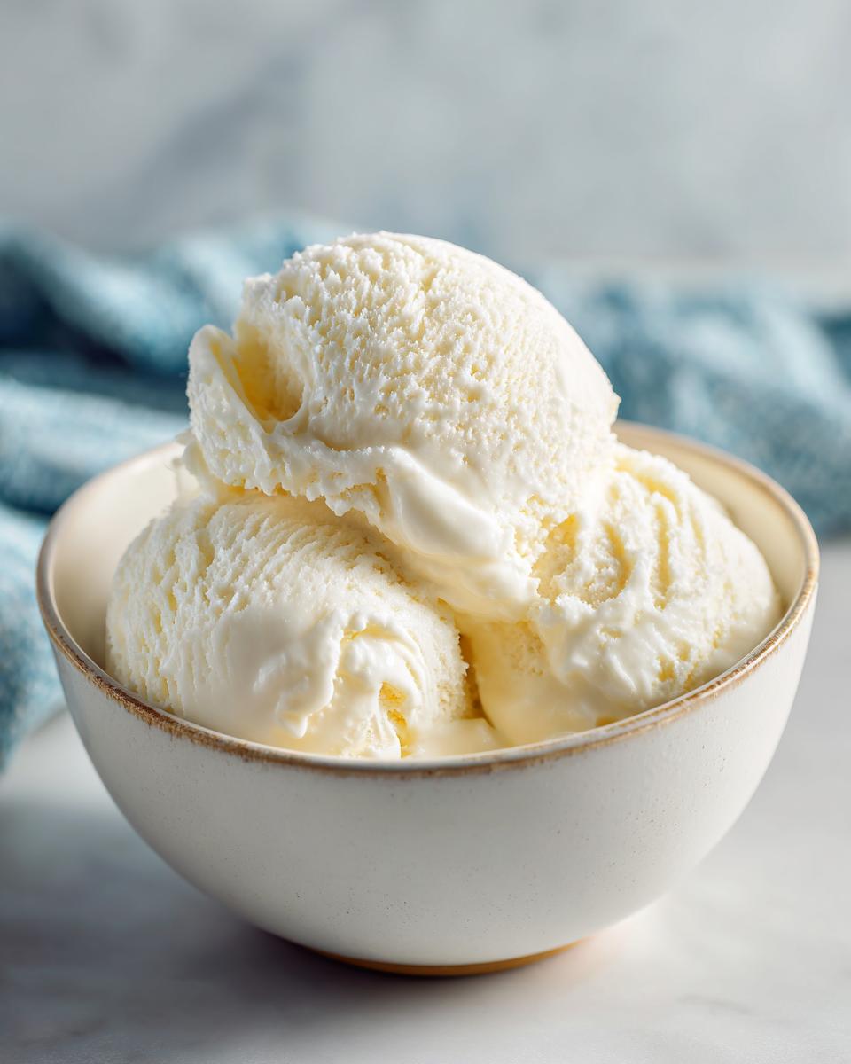 Tres bolas de helado casero de vainilla en un bol blanco sobre fondo claro