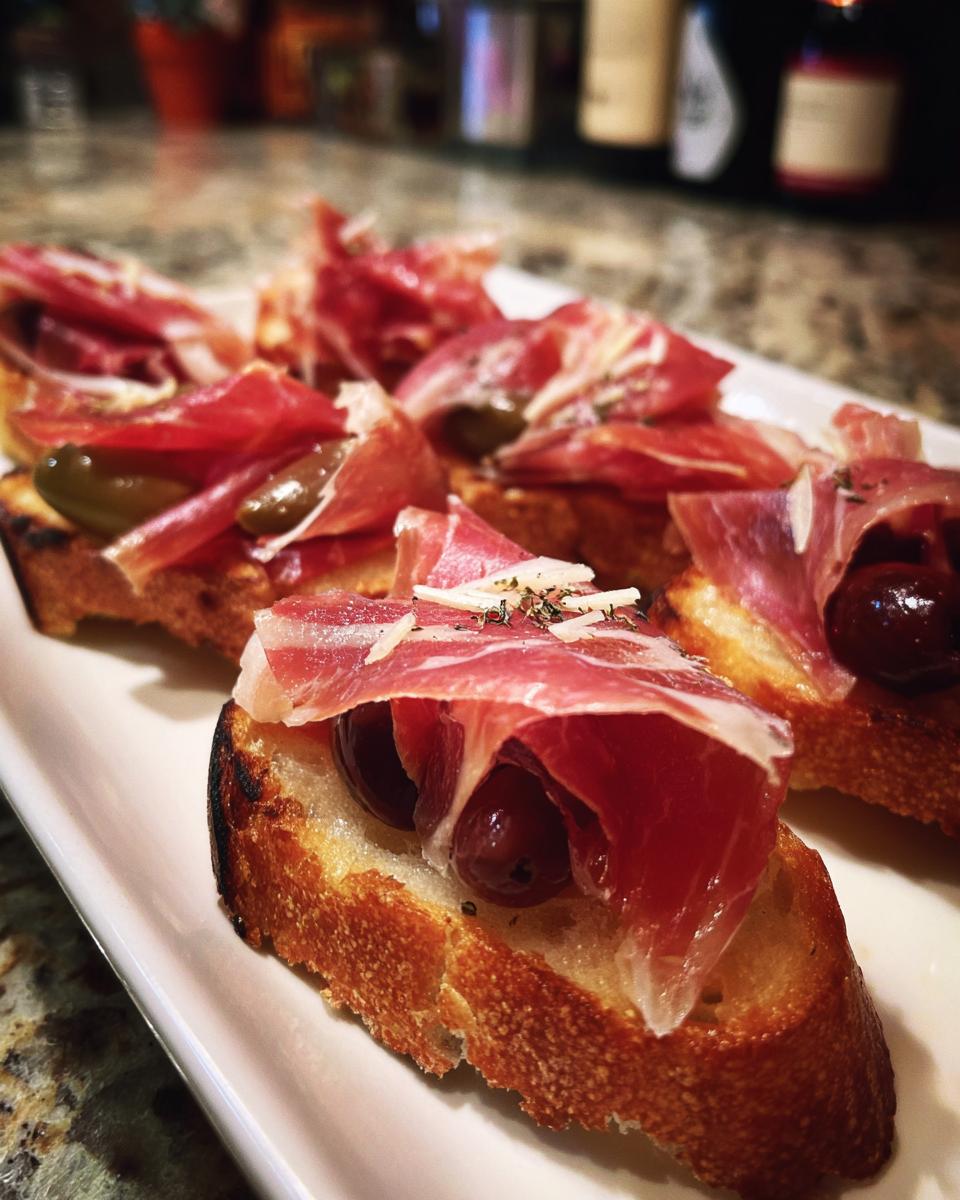 Rebanadas de pan tostado con jamón y aceitunas, tapas españolas fáciles para picar