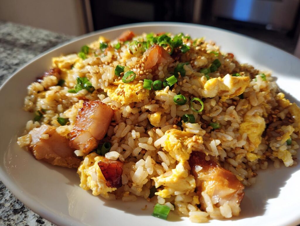 Plato de arroz chaufa con huevo revuelto, trozos de cerdo y cebolla china