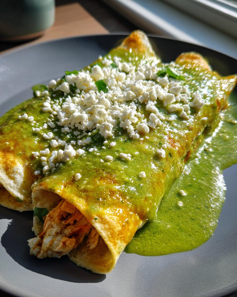Plato con enchiladas verdes caseras rellenas de pollo y cubiertas con queso fresco