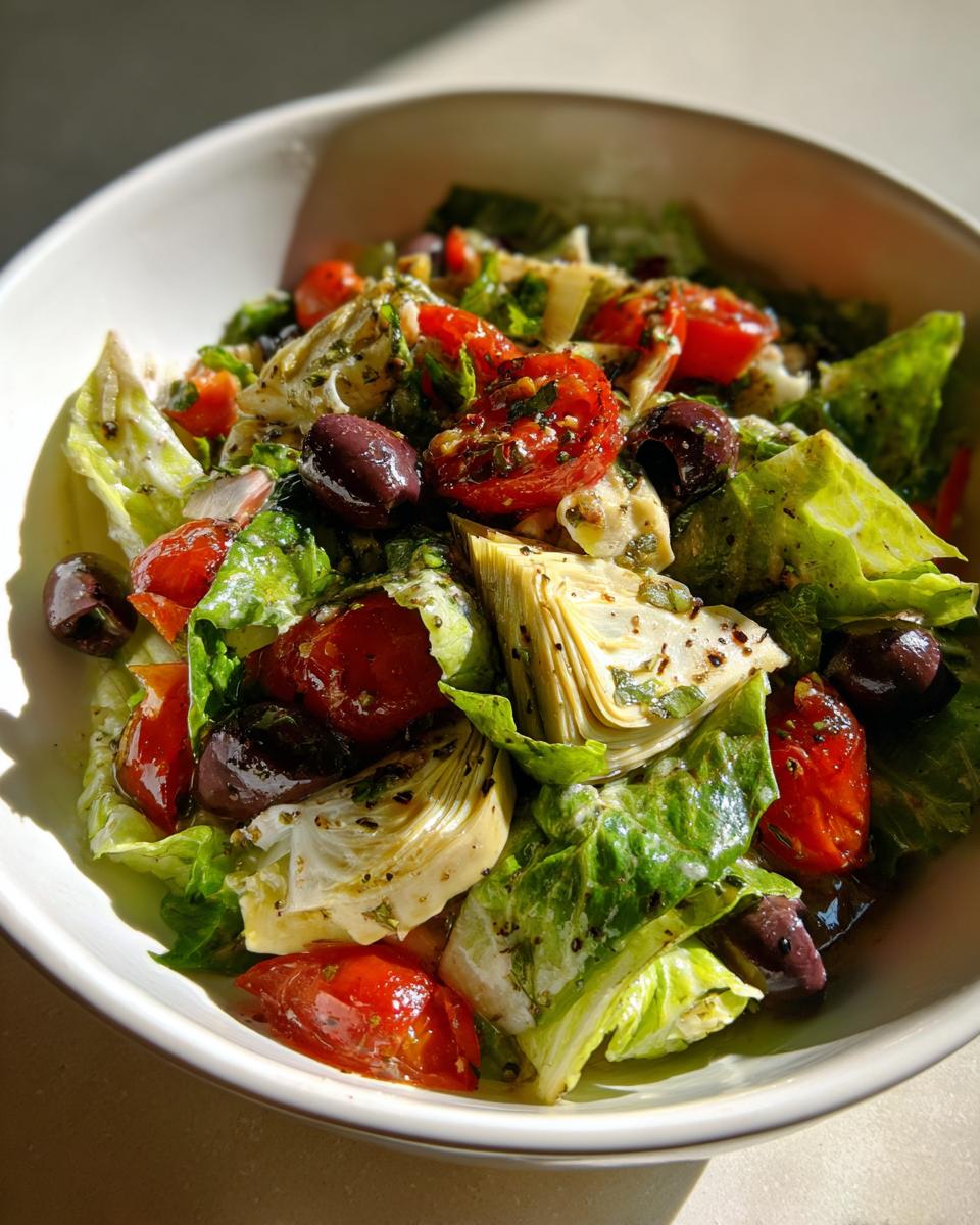Ensalada con alcachofas, tomates cherry, aceitunas negras y lechuga fresca en un bol blanco