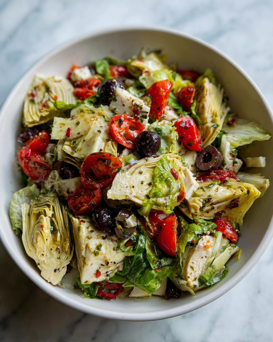 Ensalada con alcachofas, tomates cherry, aceitunas y lechuga en un bol blanco