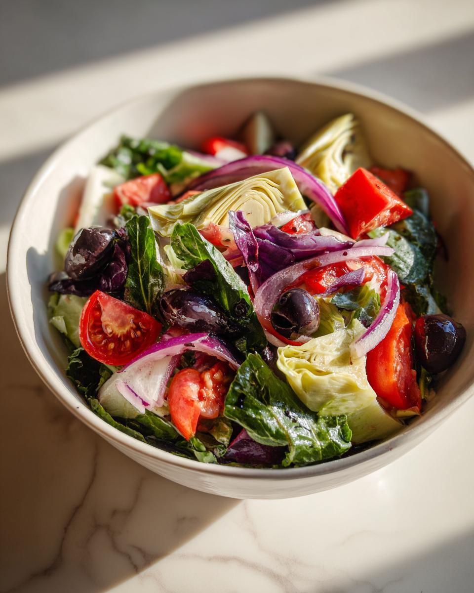 Ensalada con alcachofas, tomates, aceitunas negras, cebolla morada y hojas verdes frescas