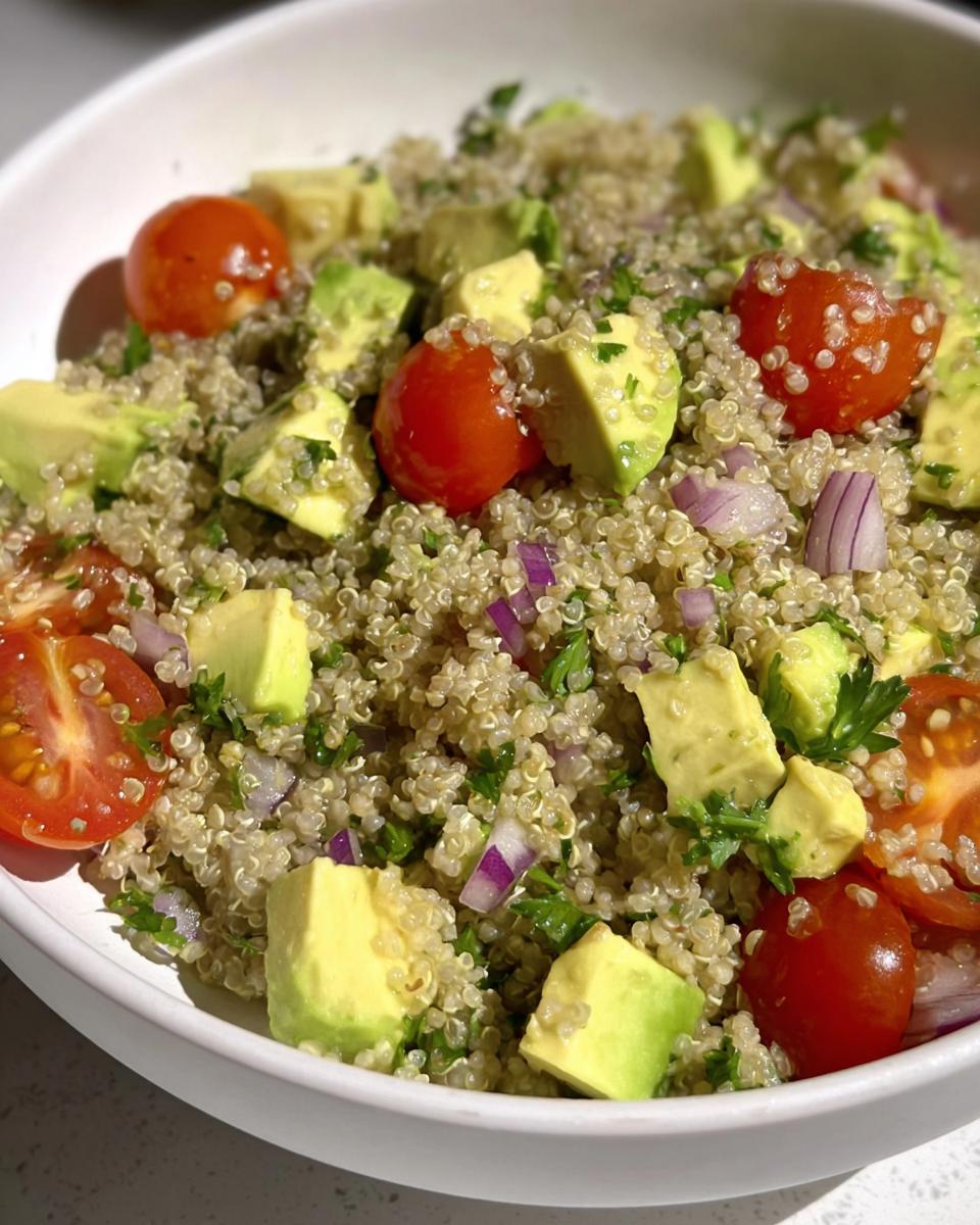 Ensalada de quinoa con aguacate, tomates cherry y cebolla morada en un bol blanco, cena rápida saludable.