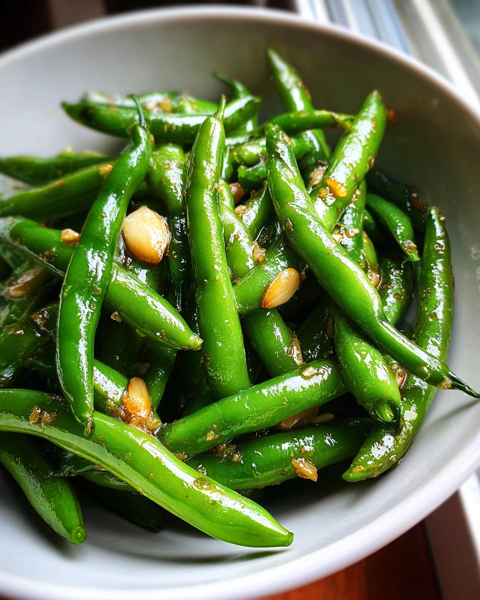 Plato blanco con habas tiernas salteadas con ajo y aceite brillante