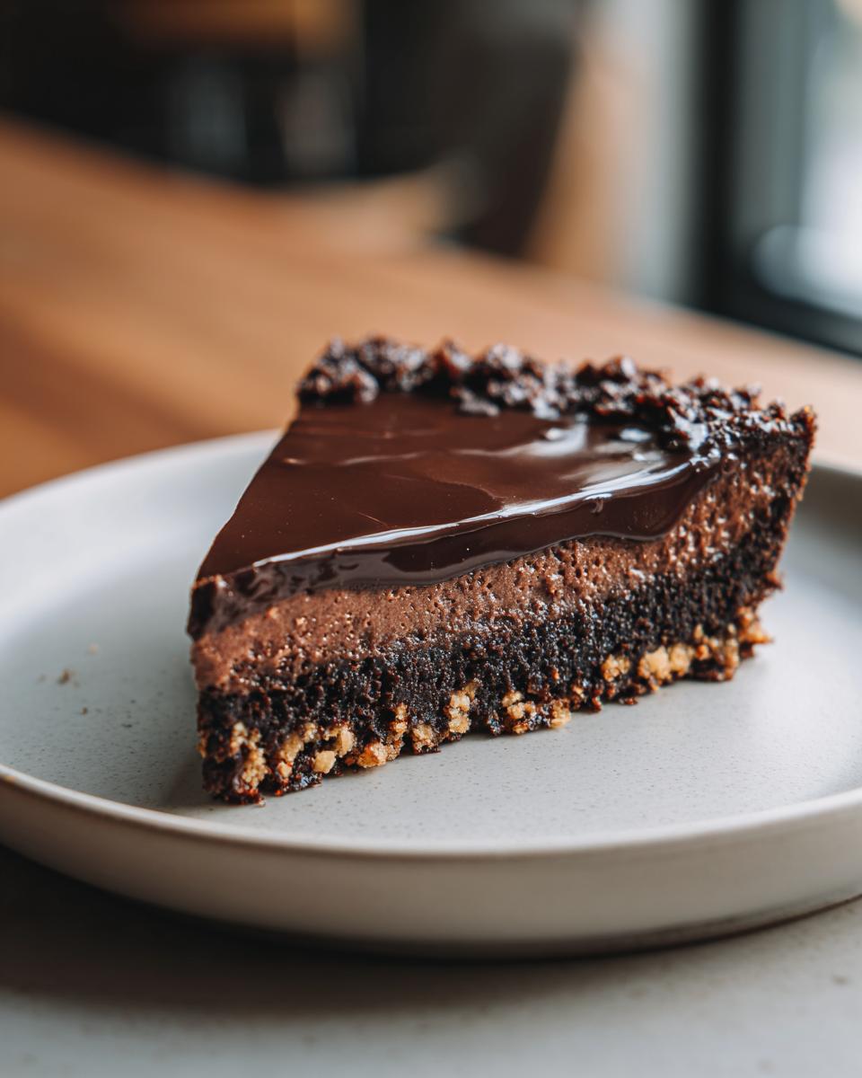 Porción de tarta de chocolate con capa cremosa y base crujiente en plato blanco