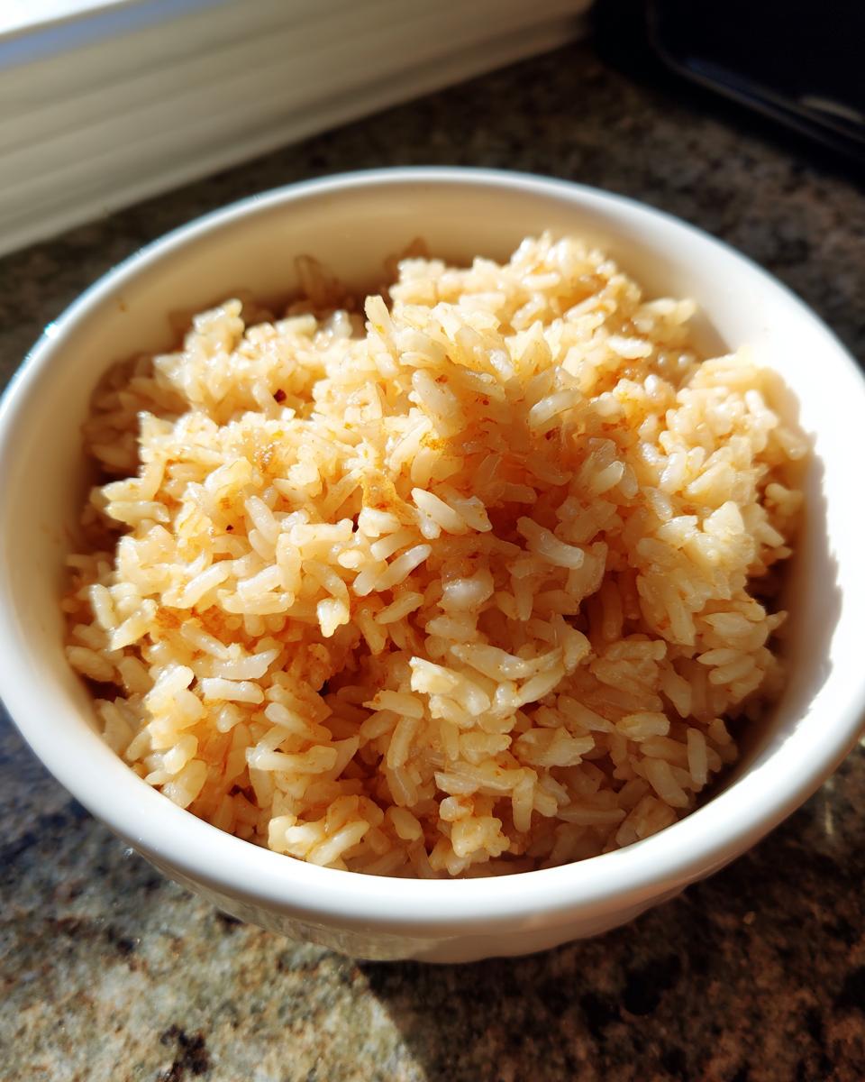 Tazón blanco con arroz mexicano cocido, con textura esponjosa y color ligeramente anaranjado.