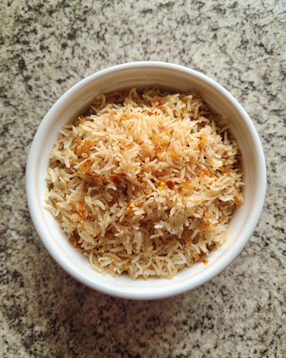 Tazón blanco con arroz mexicano especiado sobre superficie de granito.