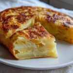 Tortilla de patatas jugosa con textura cremosa y corte triangular en plato blanco